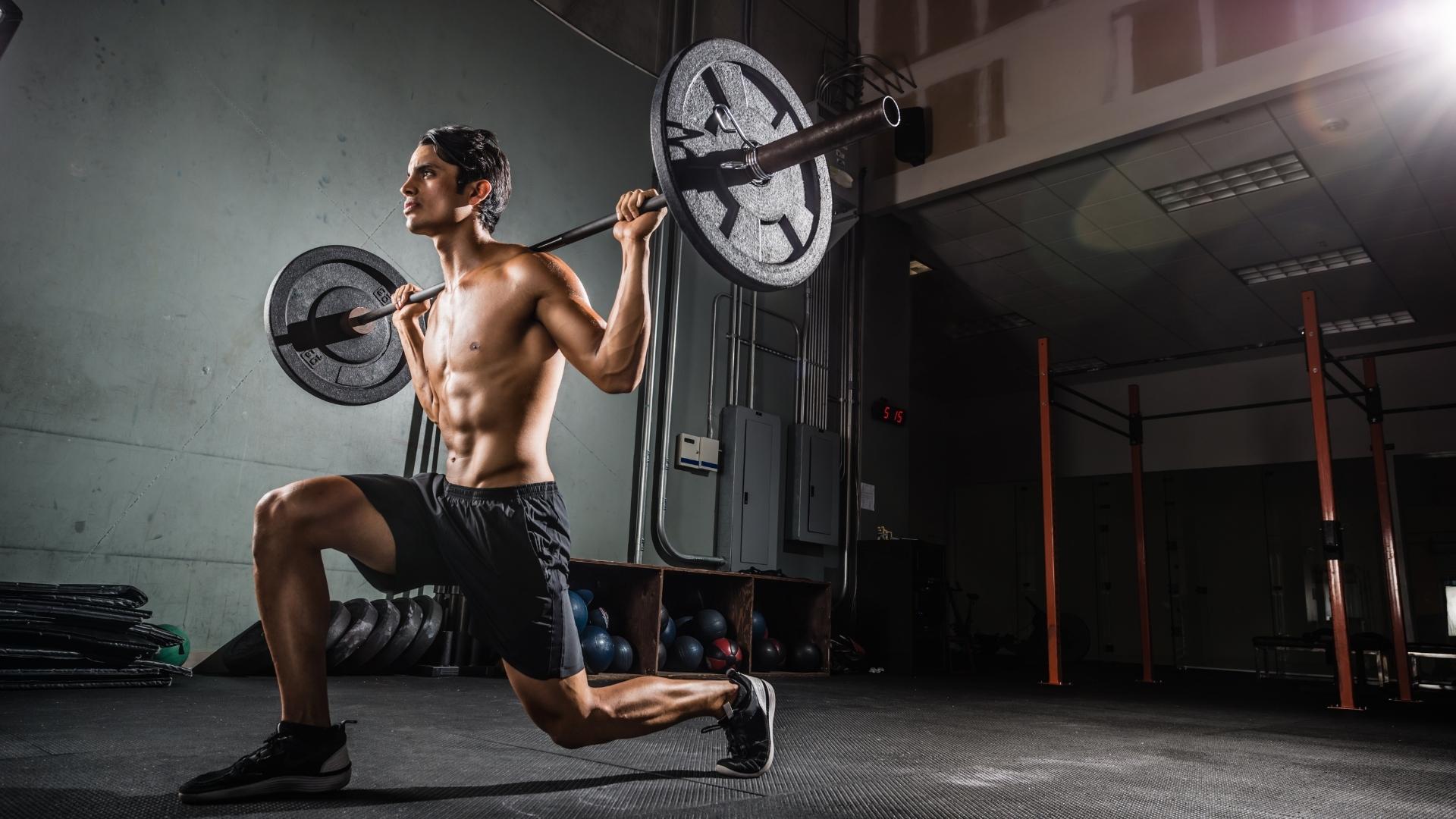 Man doing barbell lunges in the gym